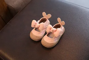 Détail de chaussures de marche roses pour bébés avec nœuds et oreilles de lapin.