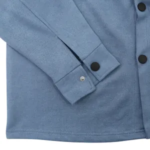 Gros plan sur le poignet d'une veste en daim bleue avec bouton-pression noir et tissu texturé