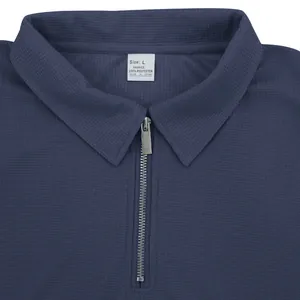 Detalle de polo azul marino de punto gofrado con una elegante cremallera plateada
