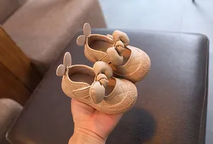 Vue détaillée de chaussures beiges pour bébé fille avec nœud et cuir surpiqué.