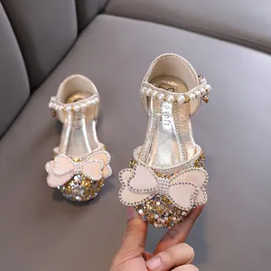 Elegant champagne girls' princess shoes with rhinestones, pearls, and a large bow.