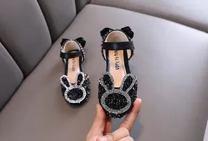 Detail of sparkly black princess shoes with rhinestone rabbit motif for girls.
