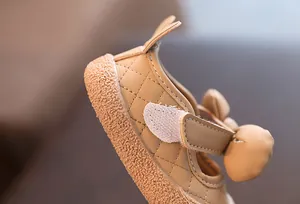 Détail de chaussure de marche pour bébé en cuir beige avec texture matelassée.