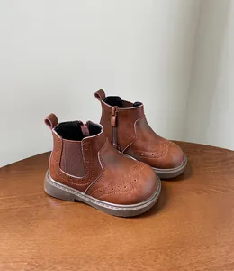 Detalle de botas retro marrones para niños con tallado brogue sobre mesa de madera