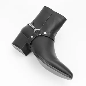 Detail view of men's black high-heel fashion boots featuring silver chain and harness strap