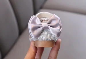 Detail showing the elegant satin bow and crystal heel of girl's silver princess shoe