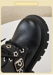 Close-up detail of black children's Martin boots featuring flower-shaped eyelets.