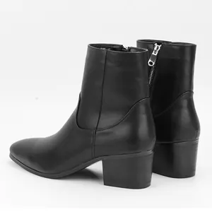 Vista detallada de botas negras para hombre con tacón de bloque y cremallera.