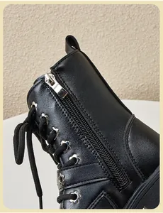 Close-up of black kids Martin boots with side zipper and floral eyelet details.