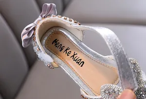 Macro view of silver glittery girls princess flats showing rhinestone details and bow.