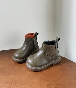 Primer plano de botas de cuero verde oliva para niños con clásicos calados brogue.