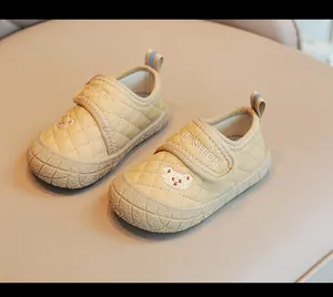 Dettaglio di scarpine primi passi beige con motivo trapuntato e ricamo a forma di orso