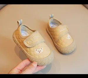 Dettaglio scarpe trapuntate beige per neonati con toppa orsetto e chiusura a strappo