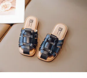 Primer plano de pantuflas trenzadas negras para niños sobre una superficie beige