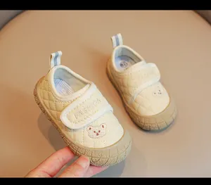 Dettaglio delle scarpe da bambino trapuntate color crema con ricamo a forma di orso