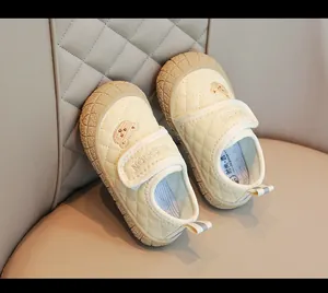 Dettaglio di scarpe trapuntate color crema per bambini con ricamo a orsetto e velcro
