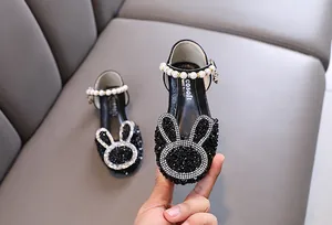 Close-up of black girls' princess shoes with rhinestone bunny and pearl strap.