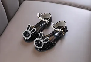 Close-up of black sequined girls shoes featuring a pearl strap and sparkling bunny ears.