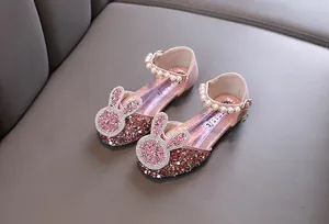 Close-up of pink sparkling girls princess shoes with pearl straps and rabbit shapes