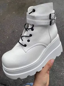 Detailaufnahme weißer Punk-Plateau-Stiefeletten mit schwarzen Schnürsenkeln und Schnallen.