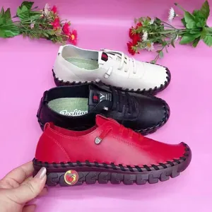 Detailopname van casual damesloafers in wit, zwart en rood met handgestikte details