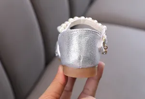 Close-up of silver girl's princess shoe heel featuring elegant pearl-embellished strap.