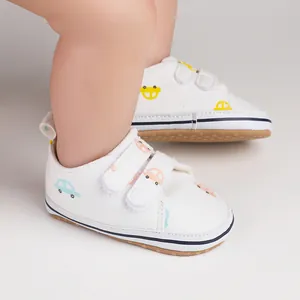 Gros plan de chaussures de marche pour bébé en toile blanche avec motifs de voitures