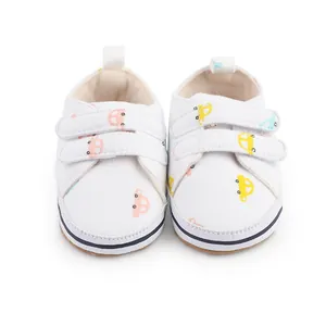 Détail de chaussures de marche pour bébé blanches avec motifs de voitures et scratchs.