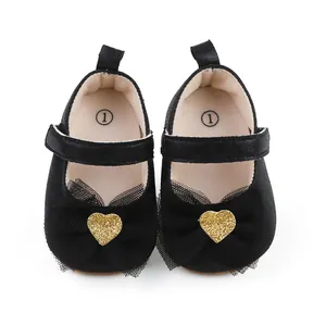 Detail von schwarzen Baby-Prinzessin-Schuhen mit Netzschleife und Goldherz-Applikation.