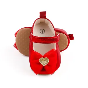 Detailansicht roter Babyschuhe mit Netzschleife und glitzerndem goldenem Herzdetail