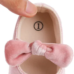 Primer plano de zapatos de bebé en terciopelo rosa con un lazo decorativo grande y elegante.