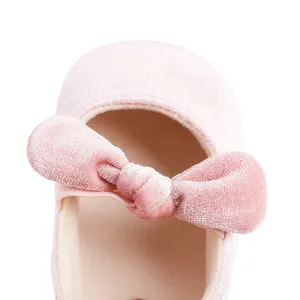 Primer plano de un zapato de bebé en terciopelo rosa suave con un lazo decorativo