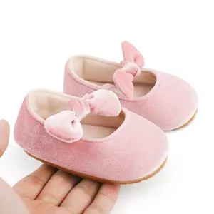 Vista detallada de zapatos de princesa de terciopelo rosa para bebé con lazo en la mano