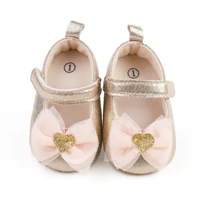 Glitzernde goldene Baby-Prinzessinenschuhe mit rosa Tüllschleifen und goldenen Herzen.