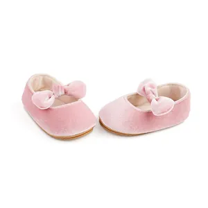 Primer plano detallado de zapatos de bebé de terciopelo rosa con lazo y suela antideslizante.