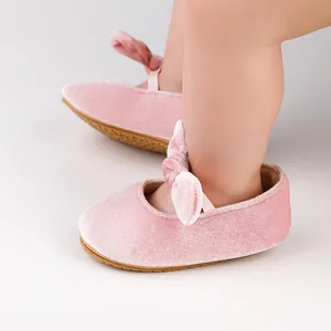 Primer plano detallado de zapatos de princesa para bebé en terciopelo rosa con un lazo.