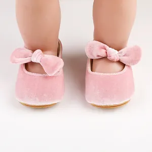 Primer plano de zapatos de princesa rosa de terciopelo para bebé con un lazo decorativo.