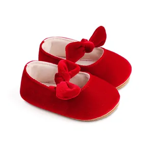 Detalle de zapatos de princesa para bebé en terciopelo rojo con un lazo decorativo.