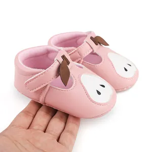 Vue détaillée de chaussures roses pour bébé avec un motif de poire tenues à la main
