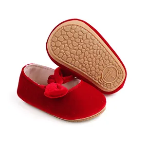Macro view of red velvet baby shoes showing the anti-slip textured rubber sole