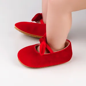 Vista detallada de zapatos de princesa para bebé en terciopelo rojo con lazo elegante.