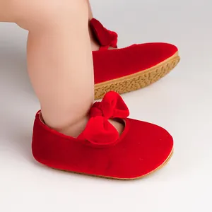 Detail view of red velvet baby princess shoes with a soft bow and non-slip sole.