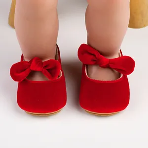 Close-up of red velvet baby shoes with large decorative bows for 0-1 year old
