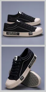Detailweergave van zwarte heren canvas sneakers met witte stiksels en beige zool.