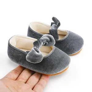 Primer plano de zapatos de princesa para bebé de terciopelo gris con lazo en la mano