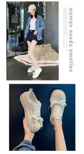 Primo piano di sneaker bianche da donna con suola spessa e lacci a fiocco decorativi