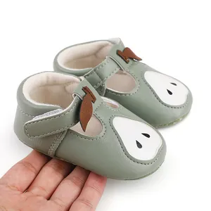 Vue détaillée des chaussures de marche bébé vert sauge avec motif poire tenues pour l'échelle