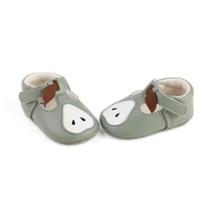 Gros plan sur des chaussures bébé vert sauge avec un motif poire mignon en cuir.