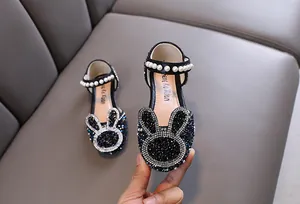 Close-up detail of girl's black princess shoes with rhinestone rabbit design and pearls