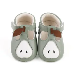 Vue de face de chaussures de marche vertes pour bébé avec un motif de poire blanche